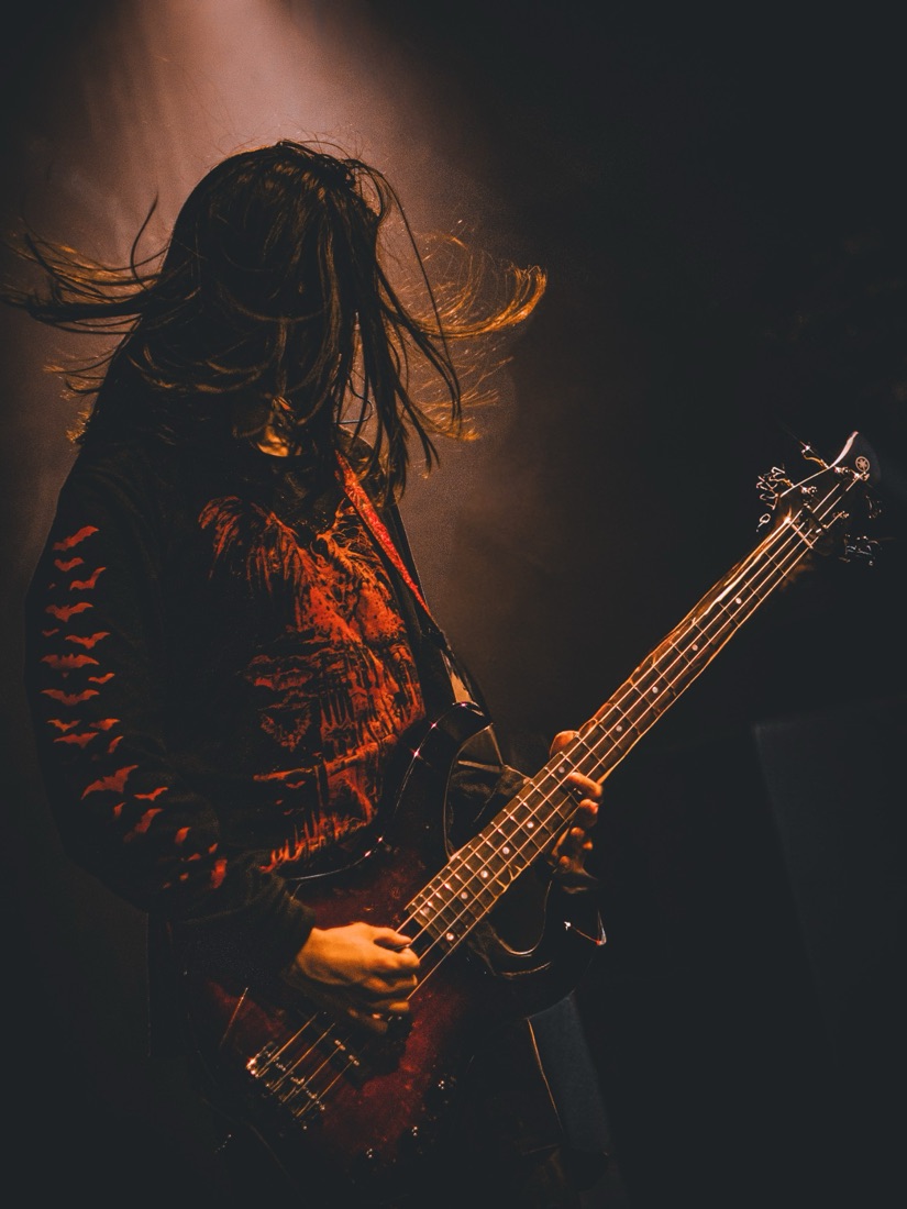 Bassist headbanging, hair flying in amber light