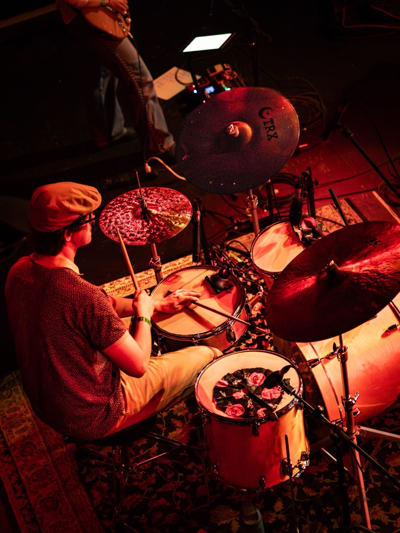 Drummer seen from above under red light on a patterned rug