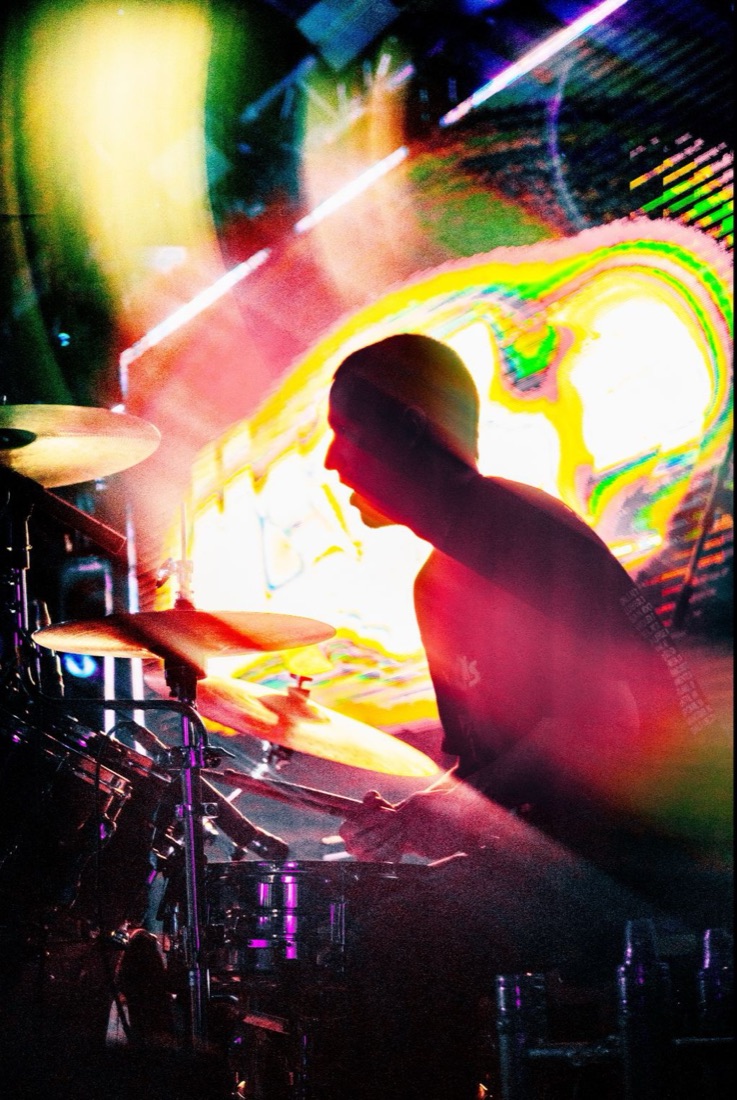 Drummer silhouetted against a psychedelic video wall
