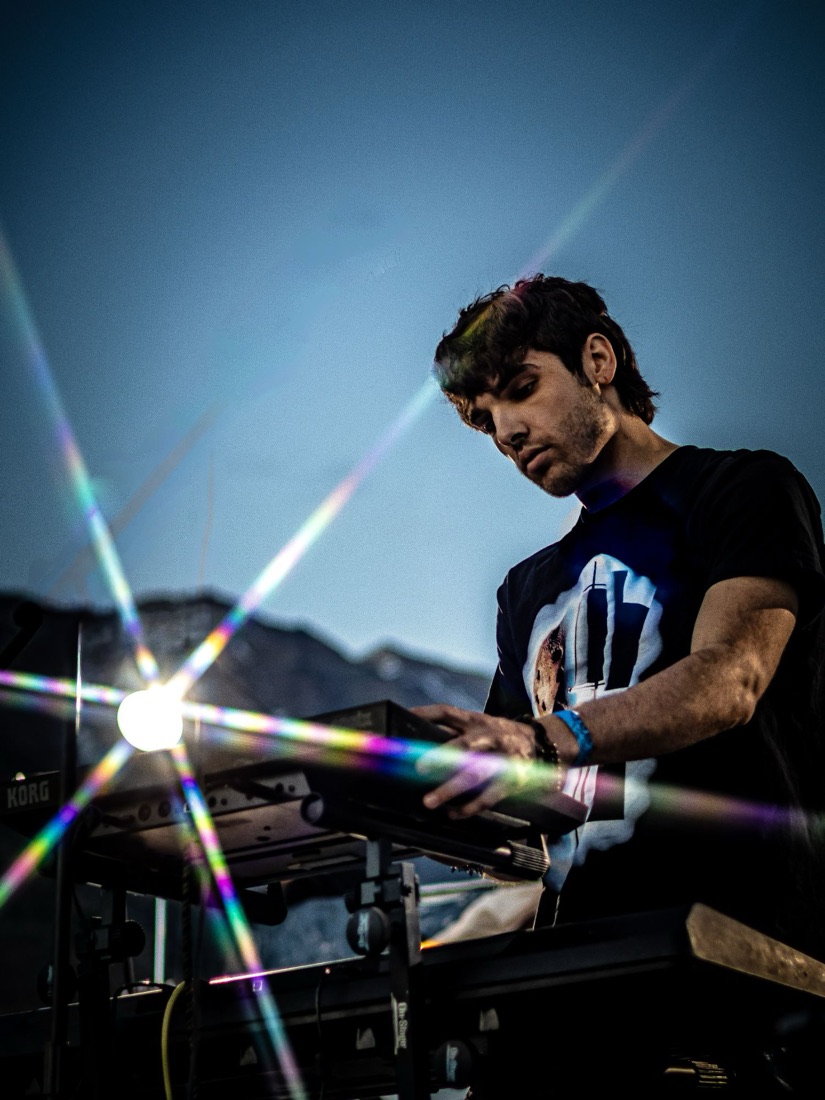 Keyboard player at an outdoor show with a rainbow starburst flare