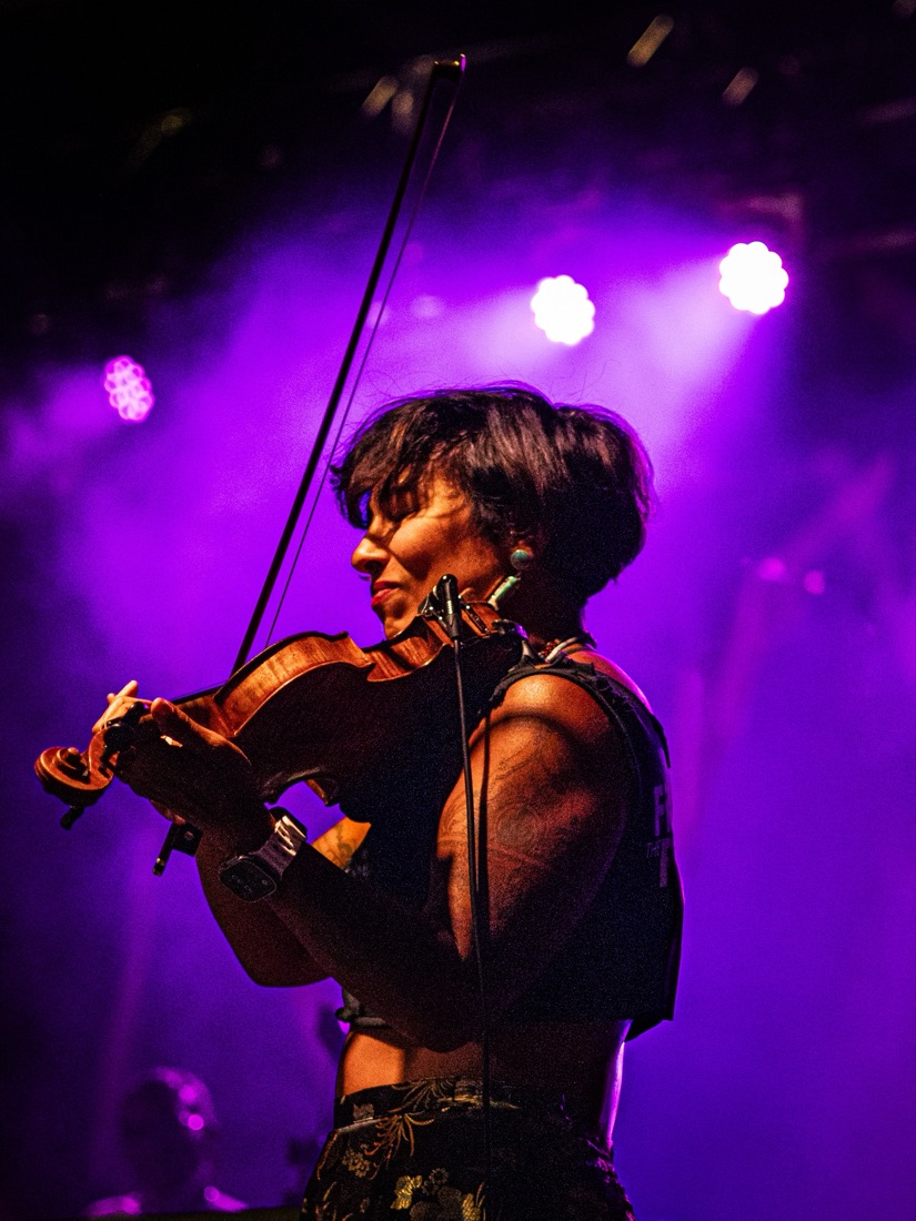 Violinist playing with eyes closed under purple stage lights